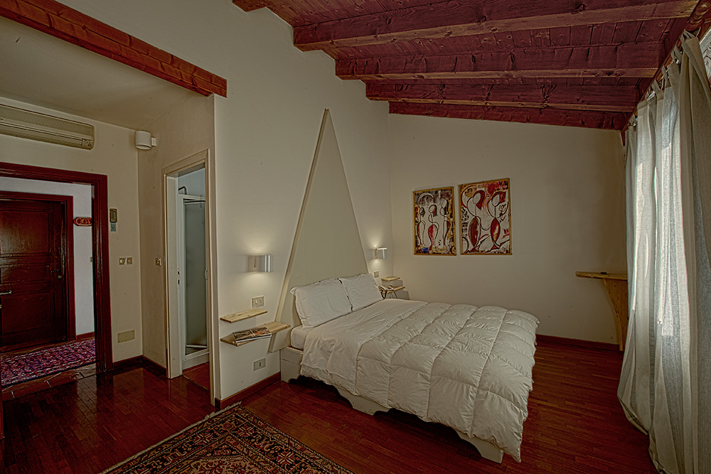 Villa Belfiore - Interno di una camera con pavimento in legno, letto matrimoniali e soffitto in travi in legno